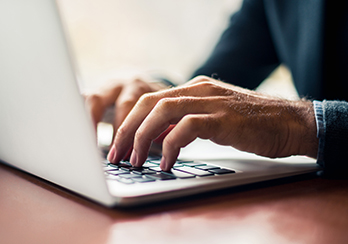Hands typing on a laptop