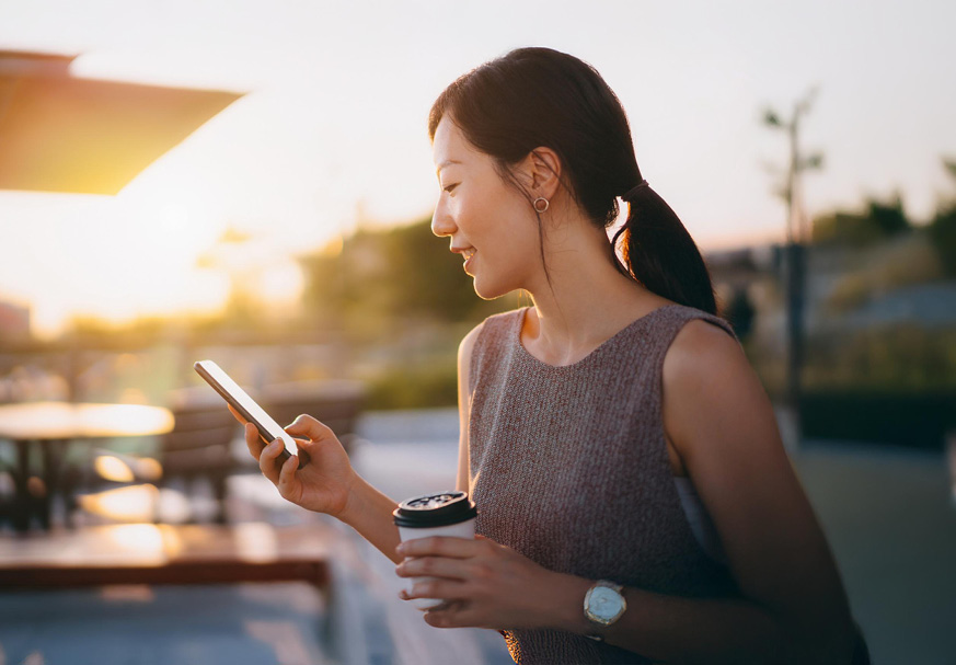 Man sitting near a wall of windows, looking at a laptop