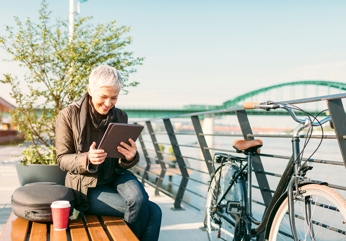 Woman outdoors sitting on bench looking at iPad