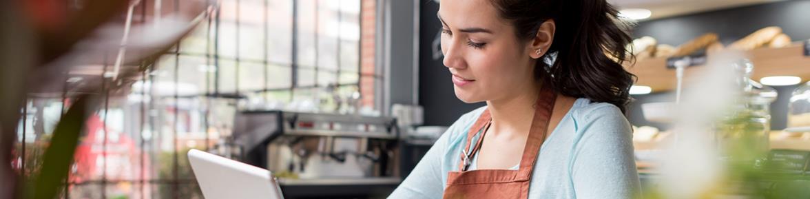 Woman sitting in an office looking at a tablet.