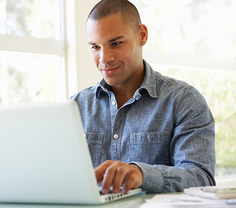 Man sitting at a table working on a laptop