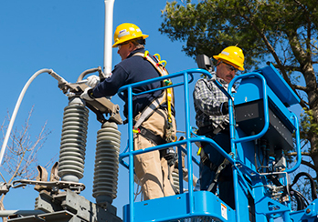 Two utility workers repairing ductwork on a rooftop