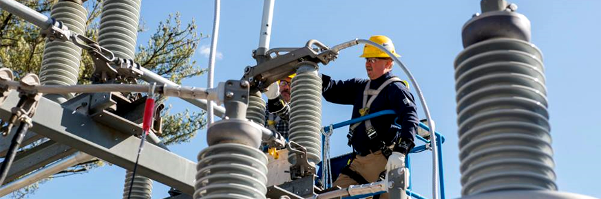 Man and woman wearing hard hats, looking at a set of construction plans