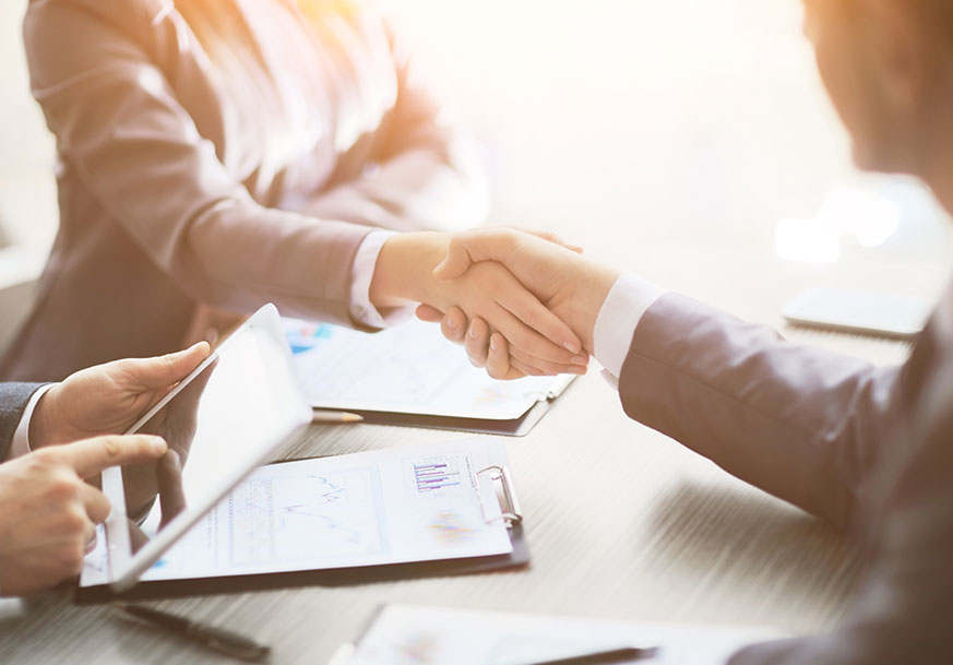 Handshake over a table with papers on it