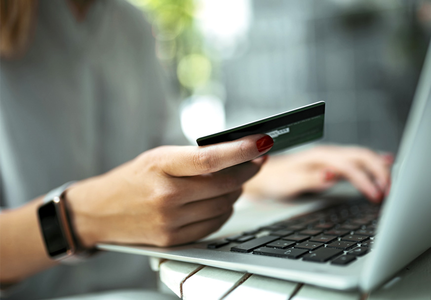 Closeup of man holding credit card and entering information into laptop